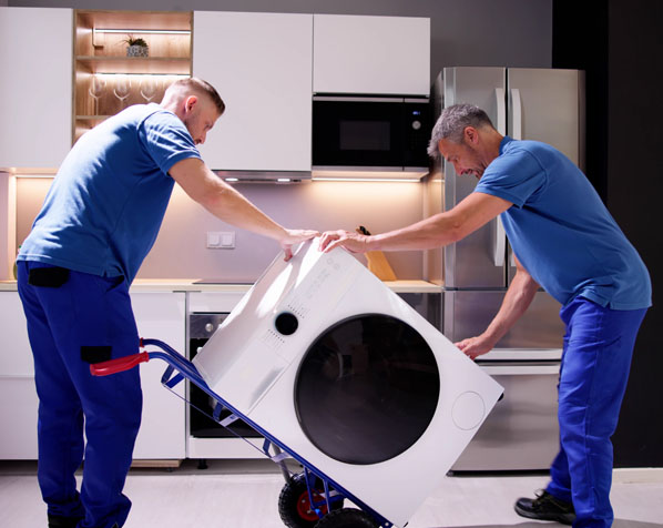 Zwei Mitarbeiter tragen eine Waschmaschine mit einer Sackkarre aus der Küche – Entrümpelung mit Wertanrechnung von Elektrogeräten.